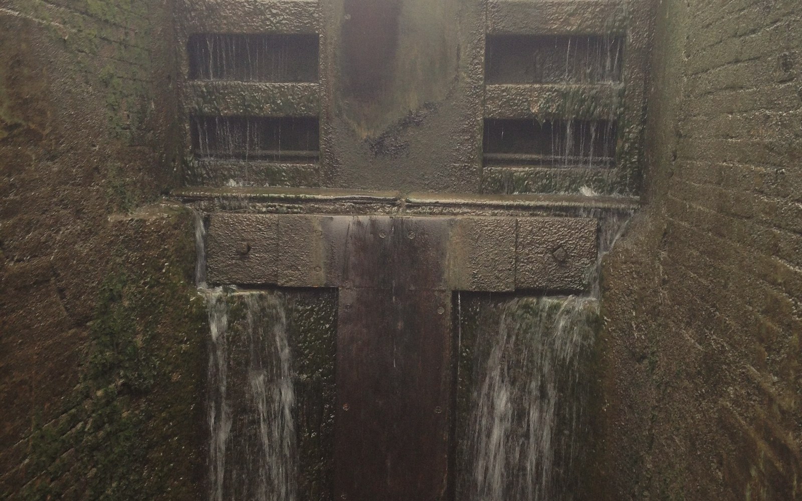 Water cascades through paddles and over wooden gates at a canal lock