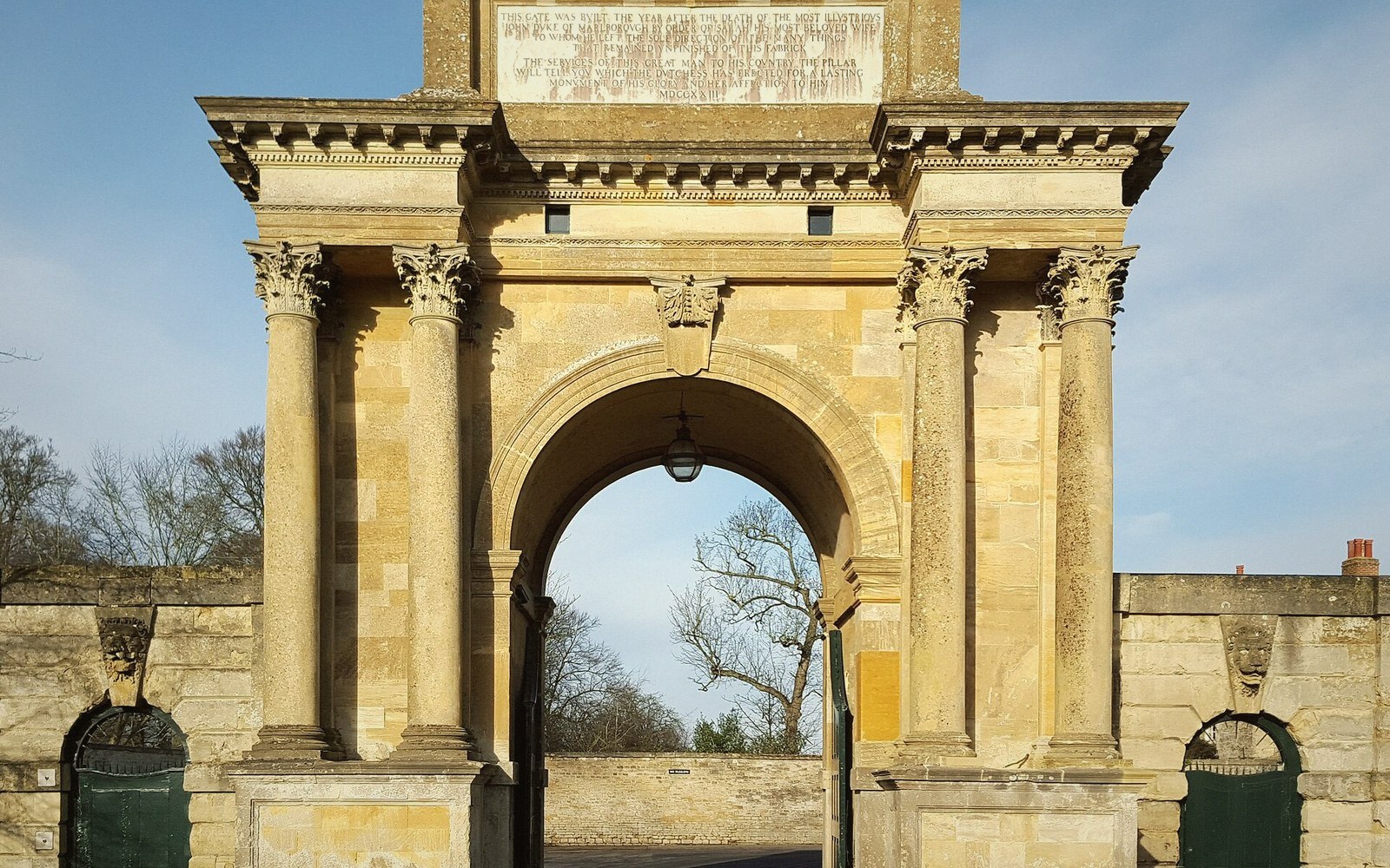Stone archway with Corinthian columns and an inscribed lintel forming a grand entrance gate