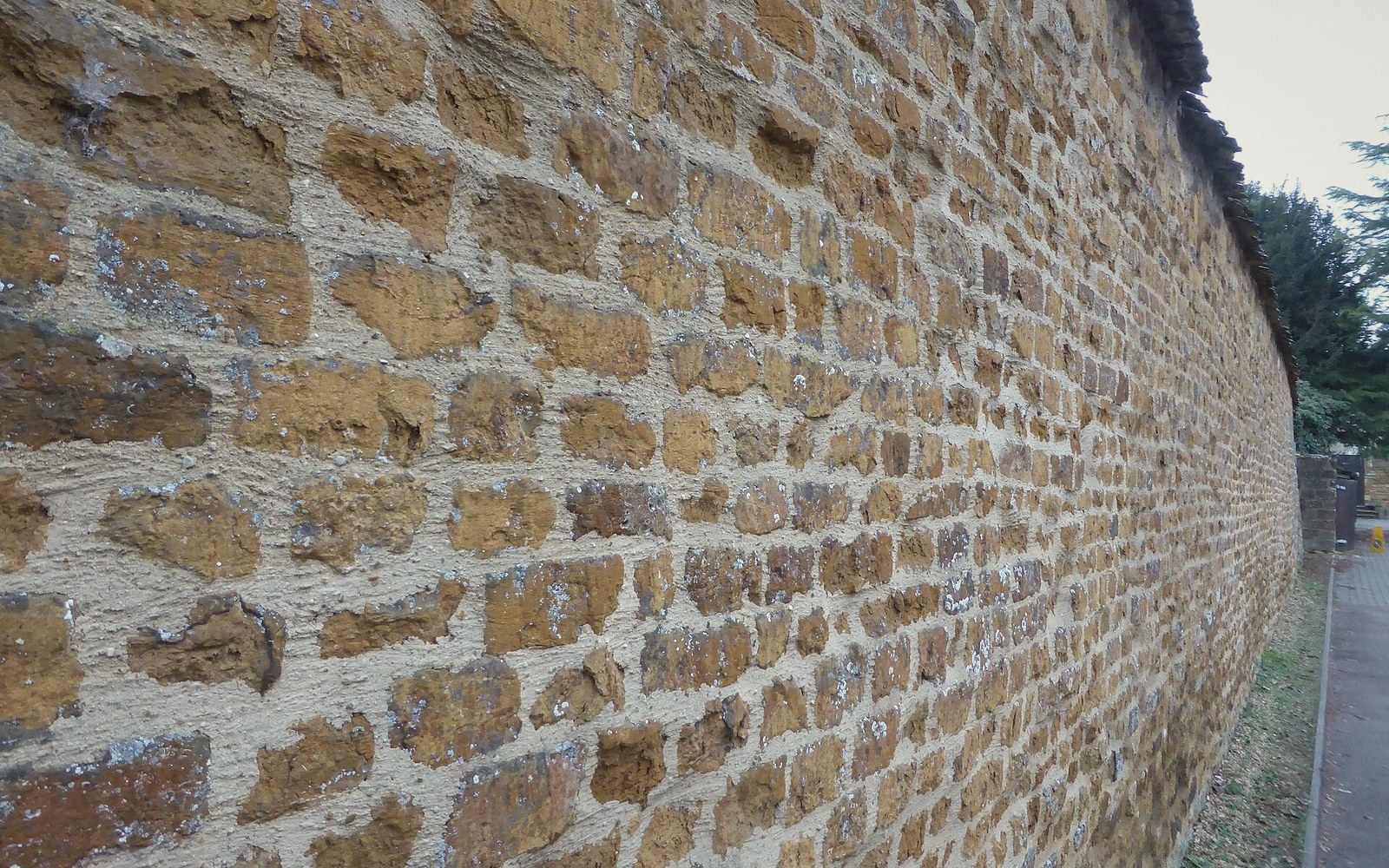 Ironstone wall in close-up, rust-brown coursed stone, mortar joints visible
